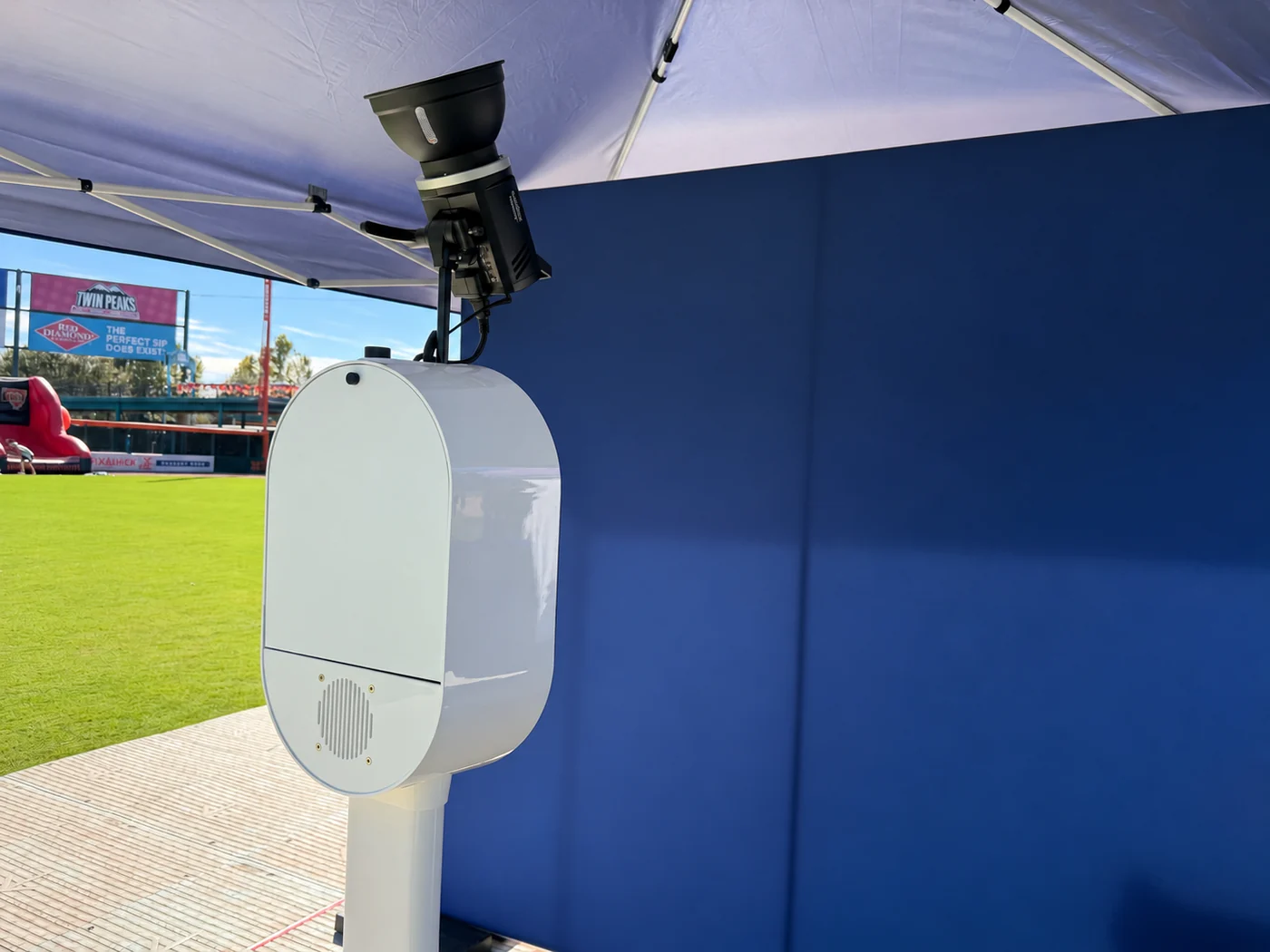 Cabina de fotos instalada bajo una carpa de festival junto a un fondo azul marino