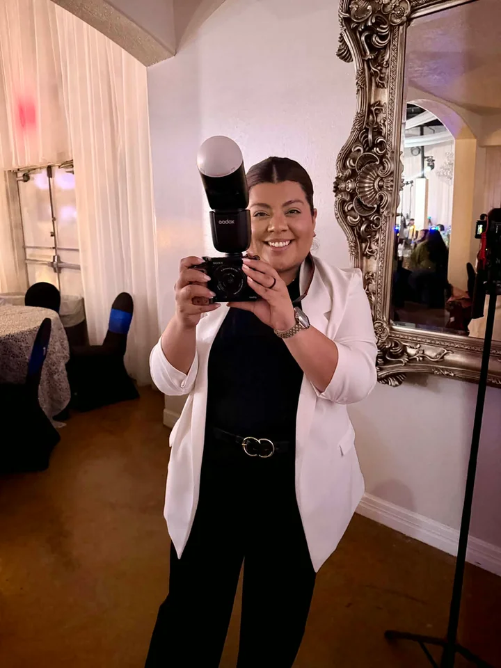 Candy smiling with a camera at an indoor event venue