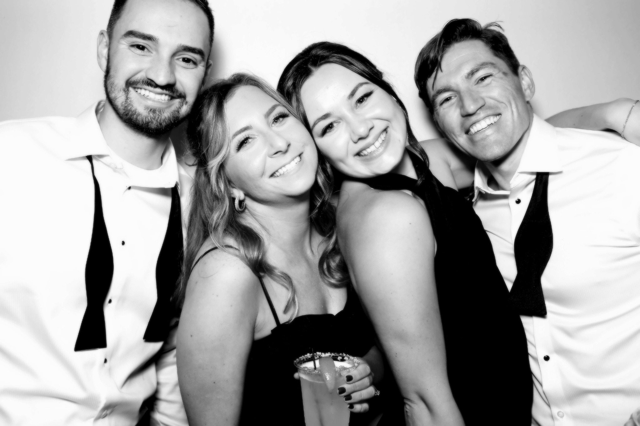 Four friends smiling together in a black and white Beauty Photo Booth portrait