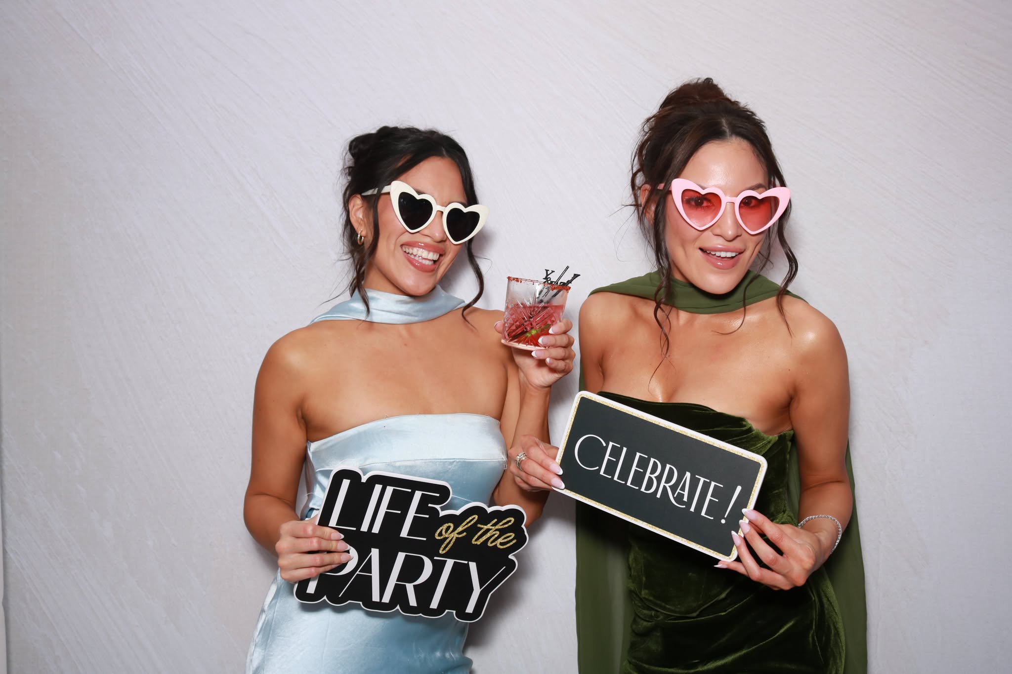 Two guests wearing heart shaped sunglasses in a color Beauty Photo Booth portrait