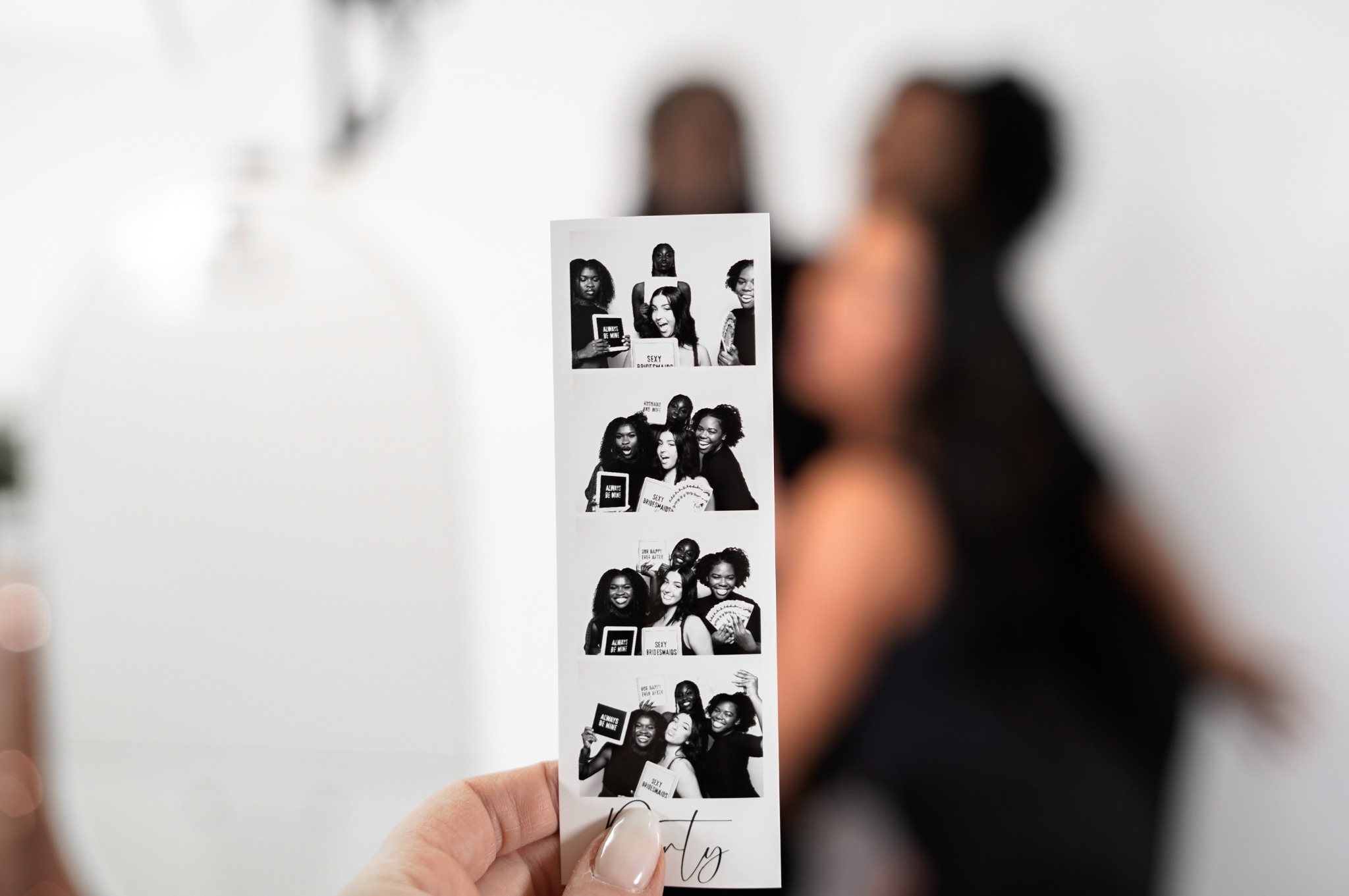 A guest holding a black and white Beauty Photo Booth photo strip