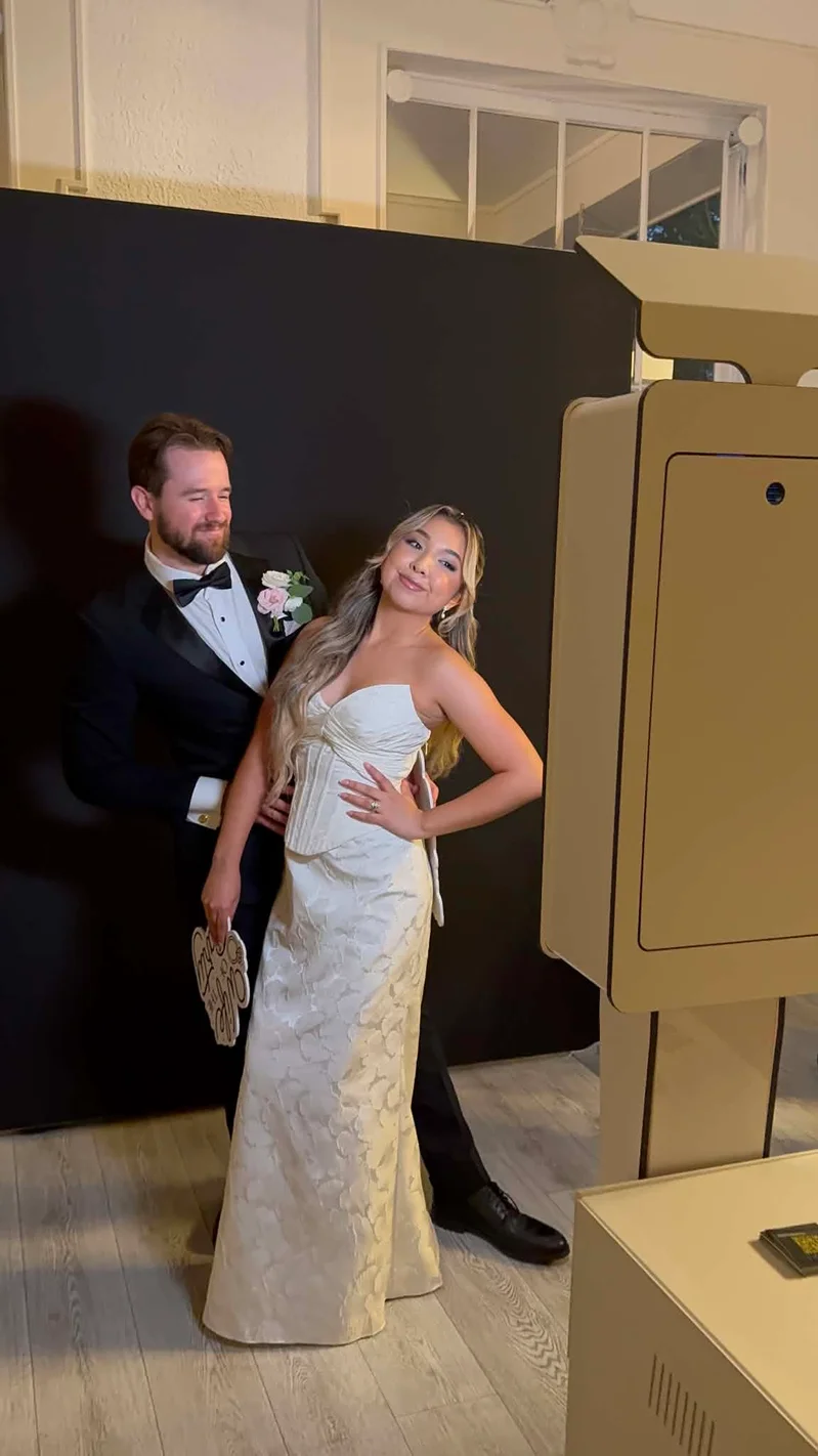 Bride and groom posing beside a Photo Booth Houston setup at their wedding