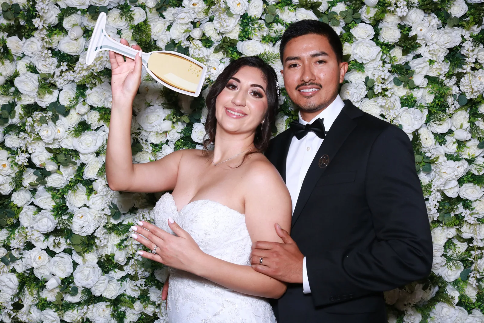 Pareja compartiendo un momento relajado frente a un muro de flores blancas